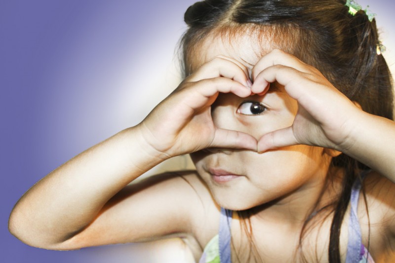 Young, compassionate girl making sign of heart with hands
