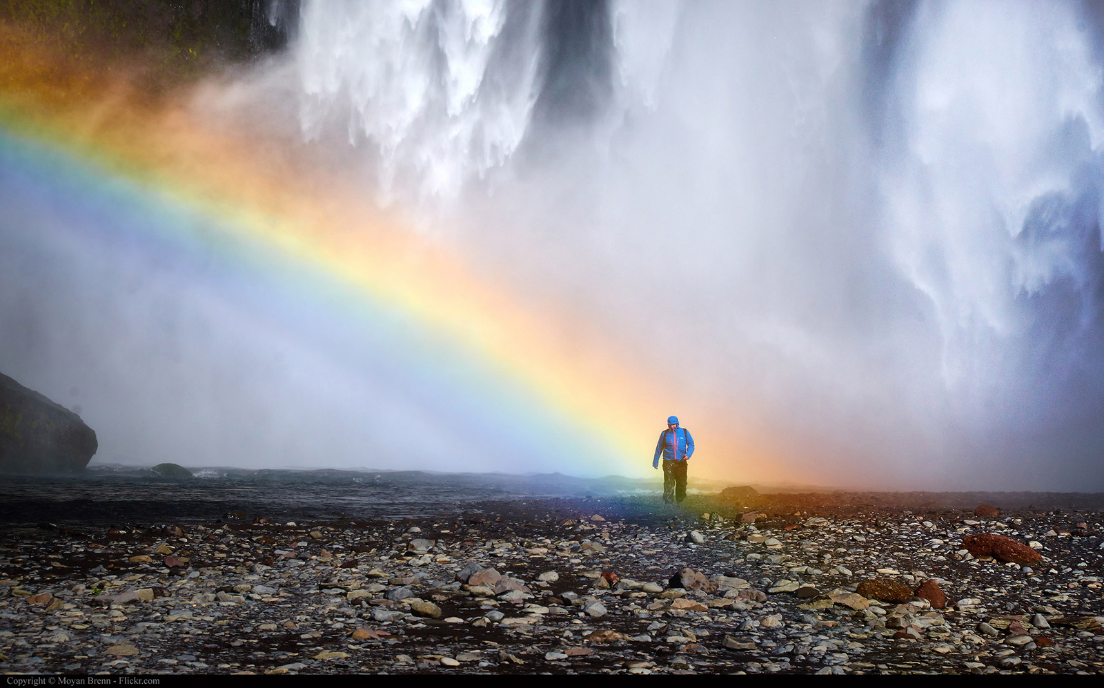 Man standing in rainbow light at Skogafoss Waterfall in Iceland