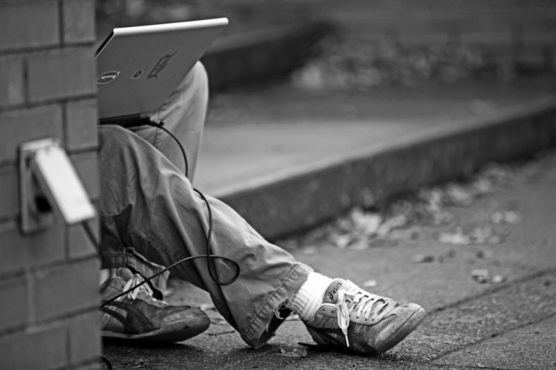 Man working on laptop in street in Portland, Oregon
