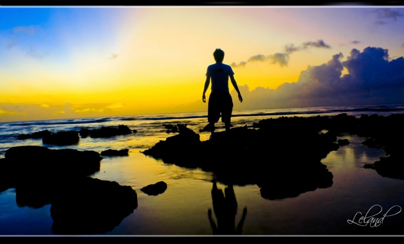 Man against yellow sunset on beach, Guam