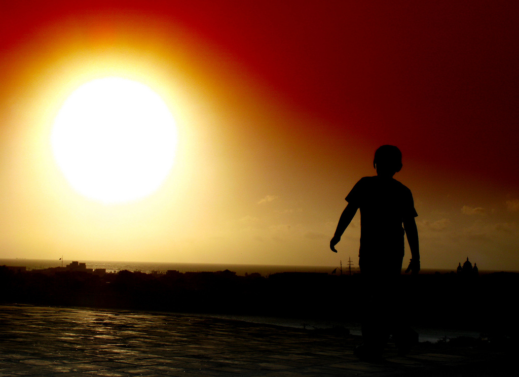 Silhouette of boy walking towards sun near Cartagena, Colombia