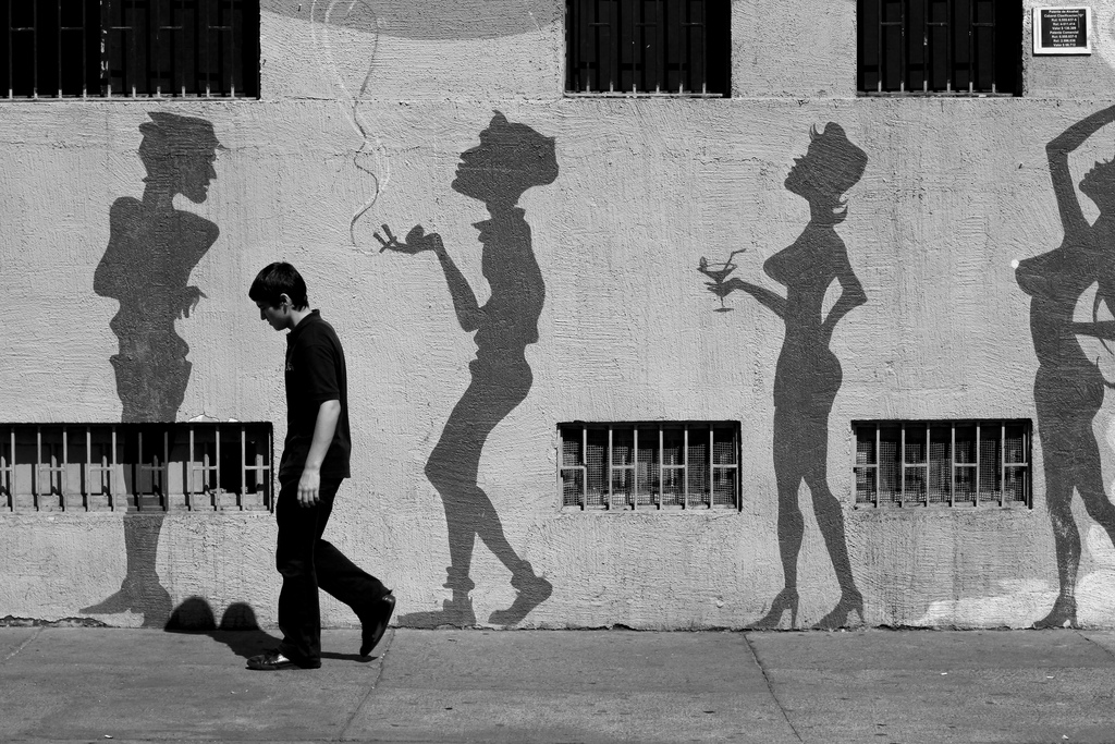 Man standing in front of street art silhouettes in Santiago, Chile